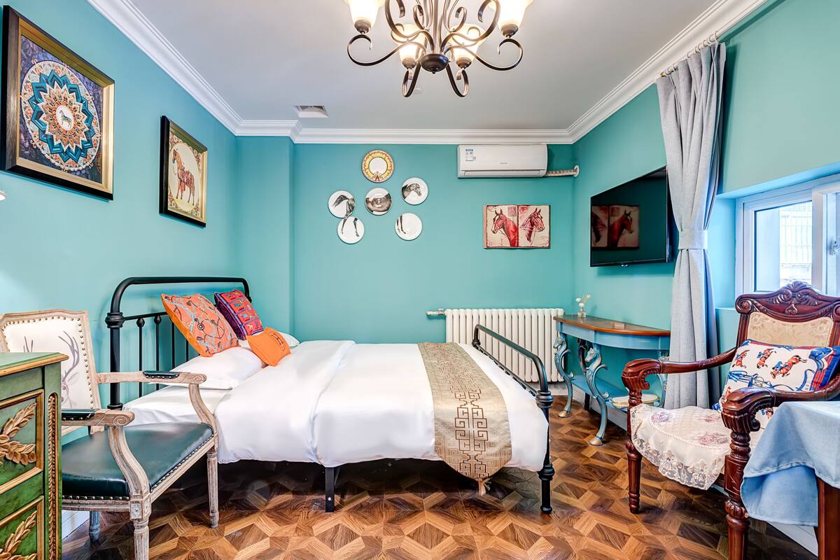Una habitación con cama, silla, mesa y un radiador.