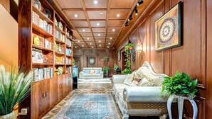 Ein geräumiger Korridor mit Holzvertäfelung, einem großen Bücherregal voller Bücher, einem Sofa und einem gemusterten Teppich.