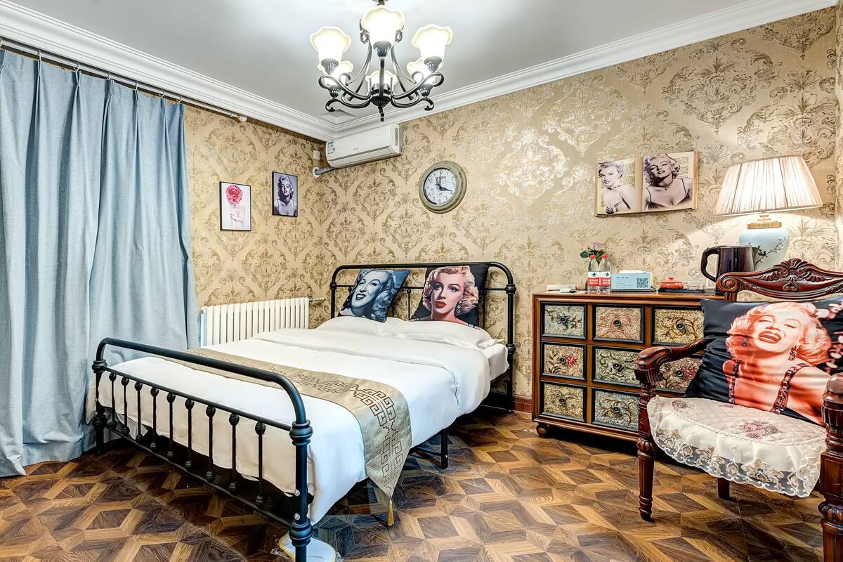 Un dormitorio con una cama, una mesita de noche de madera, una silla, un aparador y una araña.