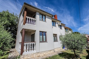 Un bâtiment à deux étages doté d’un balcon, d’une cheminée rouge et d’un chemin de pierre menant à l’entrée.
