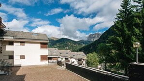 Un patio con pavimento de adoquines, un edificio con tejado de tejas y una montaña al fondo.