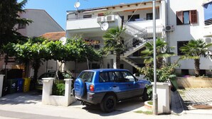 A blue car parked in front of a building with a balcony and a staircase leading to an upper floor. - Cozy apartment Buterer (Rovinj)