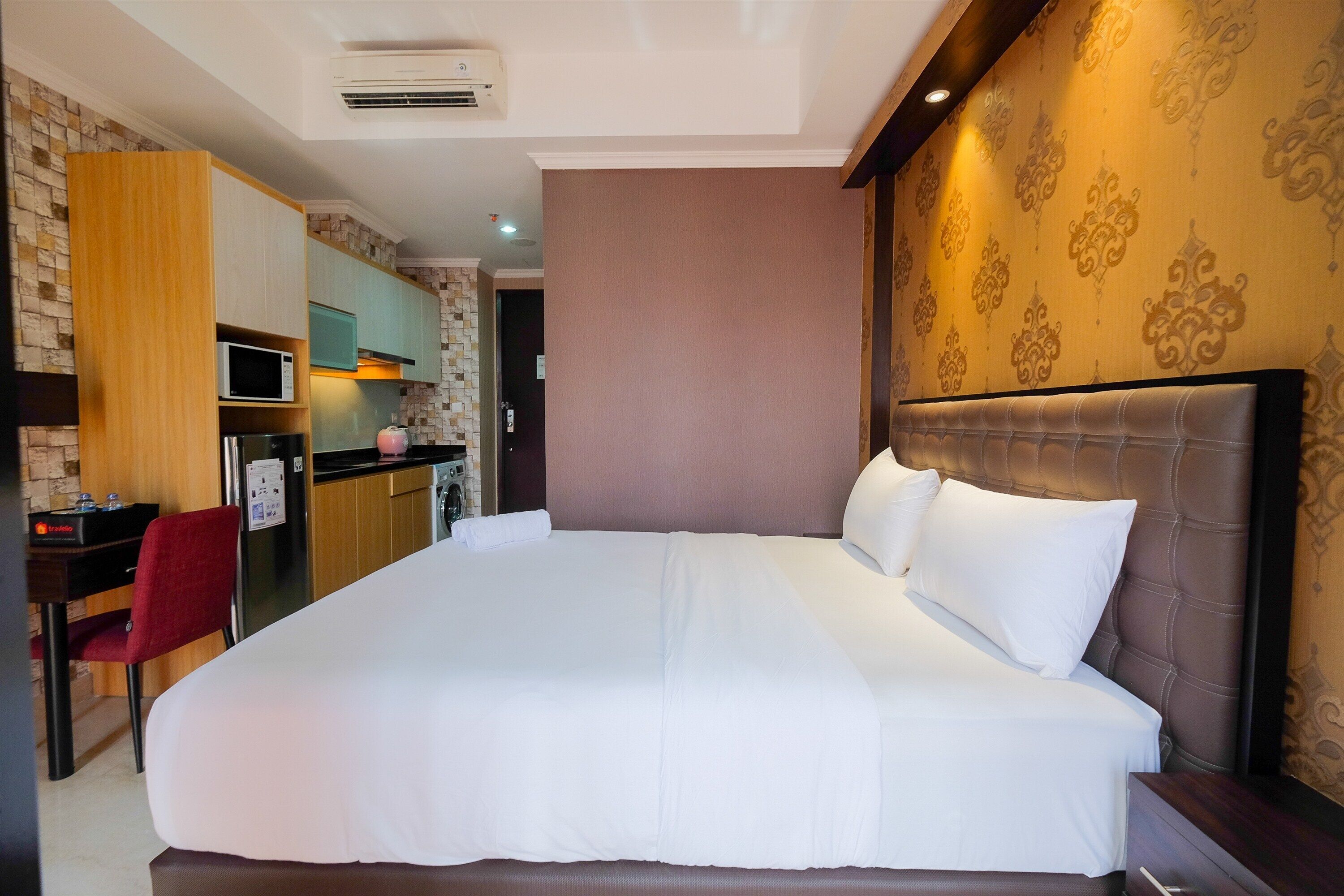 Habitación de hotel con una cama grande, un escritorio con silla, un microondas y una kitchenette.