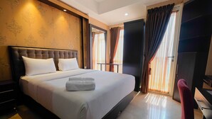 A hotel room with a large bed, a desk, and a chair.