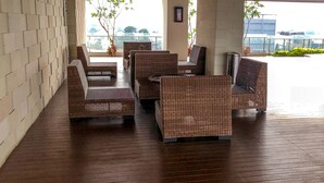 Een overdekt terras met rieten meubels en een houten vloer.