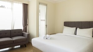 Een hotelkamer met een bed, een sofa en een raam met gordijnen.