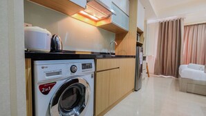 A compact kitchen with a built-in washer and dryer, wooden cabinets, and a modern design. - Cozy Studio Room Apartment Menteng Park (Jakarta)