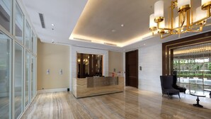 A modern lobby with a marble floor, a reception desk, and a seating area with a view of the outdoors. - Cozy Studio Room Apartment Menteng Park (Jakarta)