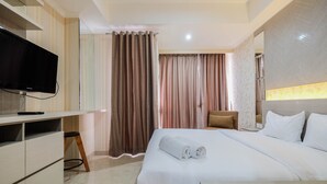 A hotel room with a bed, a TV, a desk, and a chair. - Cozy Studio Room Apartment Menteng Park (Jakarta)