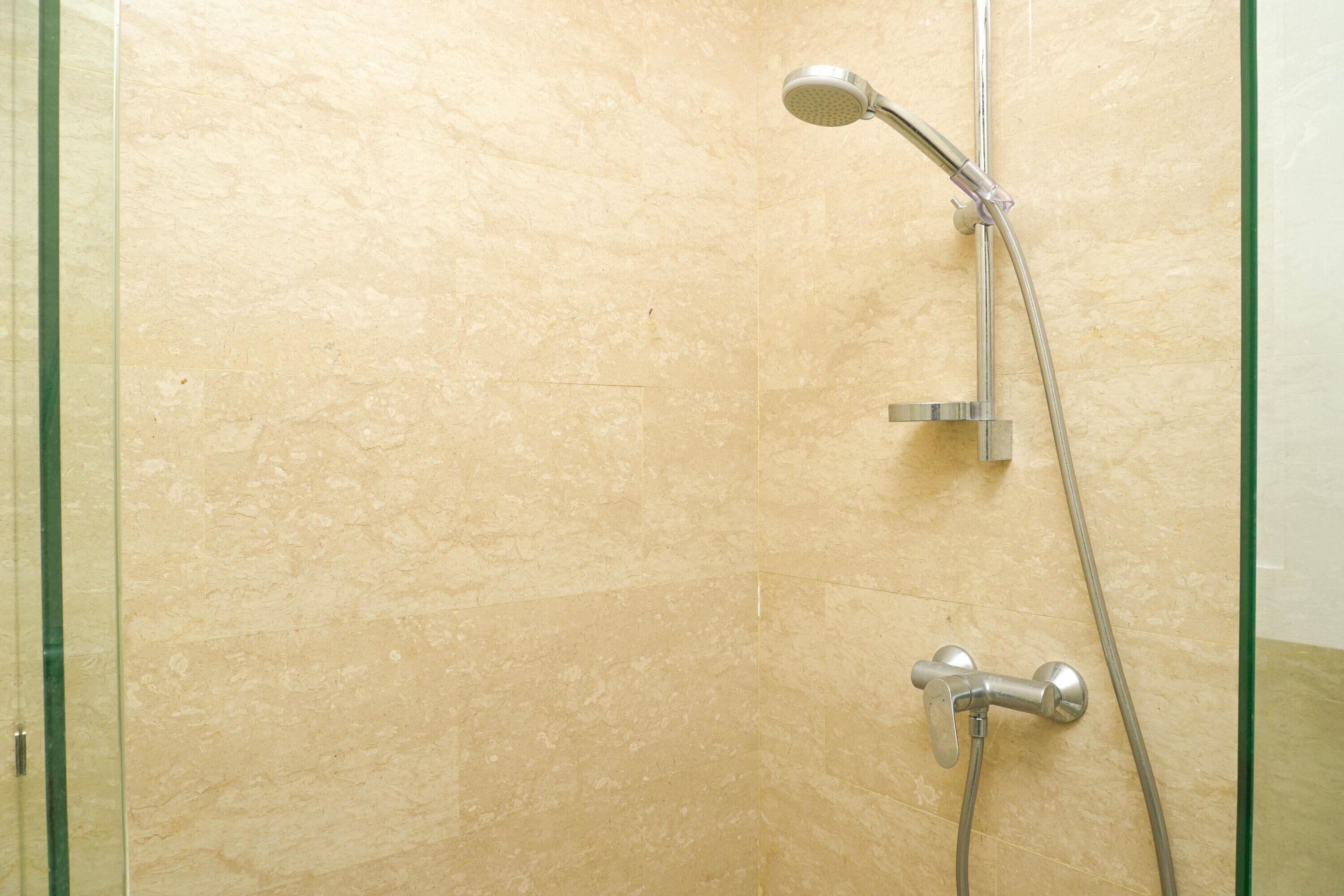 Ducha con mampara de vidrio y cabezal de ducha manual.