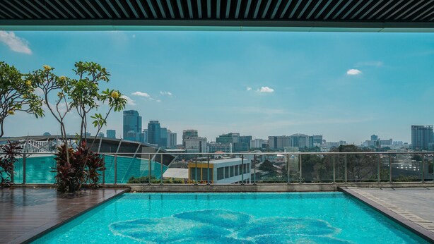 A rooftop pool with a city view, surrounded by plants and a glass railing. - Elegant Studio at Menteng Park Apartment (Jakarta)