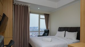 A hotel room with a large bed, a desk, a chair, and a TV mounted on the wall. - Elegant Studio at Menteng Park Apartment (Jakarta)