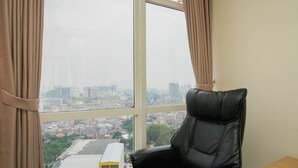 A room with a large window, a black leather chair, and a small wooden table. - Elegant Studio at Menteng Park Apartment (Jakarta)