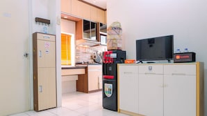 Eine kleine Küche mit Mikrowelle, Kaffeemaschine und einem Fernseher auf einem Schrank.