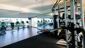 A gym with various exercise machines, a mirrored wall, and large windows. - Modern and Cozy Studio Menteng Park Apartment (Jakarta)
