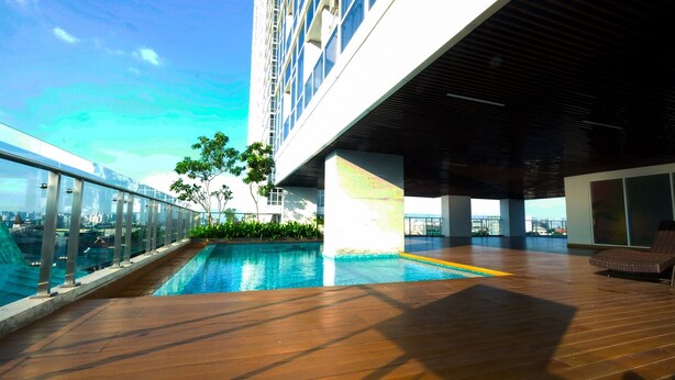A rooftop pool area with a clear view of the city skyline, a covered seating area, and a wooden deck. - Modern and Cozy Studio Menteng Park Apartment (Jakarta)