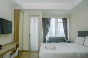 Une chambre d’hôtel avec un lit, une télévision, un bureau et une chaise.
