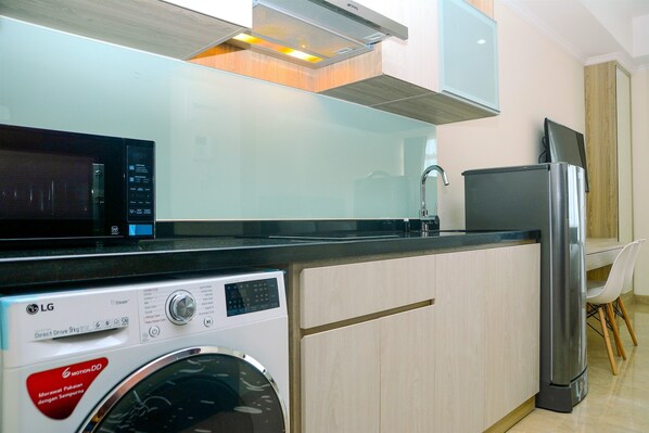 Cozinha compacta com máquina de lavar, micro-ondas, frigorífico e forno embutido.