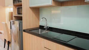 Une cuisine moderne dotée d’un réfrigérateur en acier inoxydable, d’un plan de travail noir, d’un évier et d’armoires en bois.
