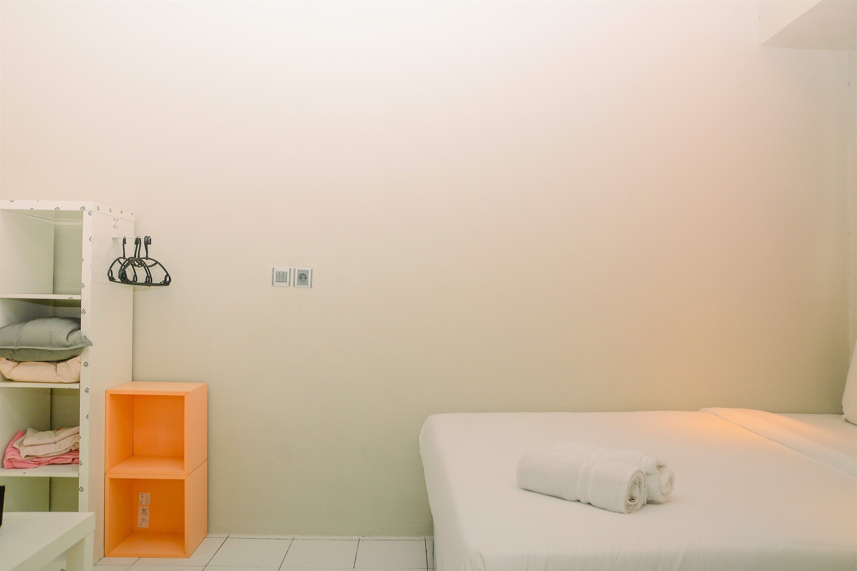 Un dormitorio con una cama, un armario blanco y una estantería naranja.