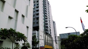 A tall, modern building with multiple balconies and a flag on top. - City View Studio Apartment at Menteng Square (Jakarta)