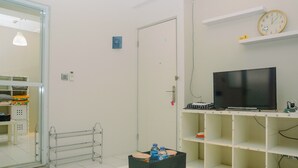 A room with a television on a shelf, a door, and a rack with bottles. - City View Studio Apartment at Menteng Square (Jakarta)