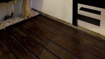 A modern bathroom with a white sink, wooden floor, and decorative wall panels.