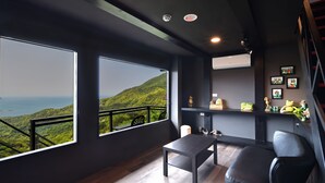 A modern room with large windows offering a view of a lush green landscape and the sea. - Windsor's Sunlight Han-Guan (New Taipei City)