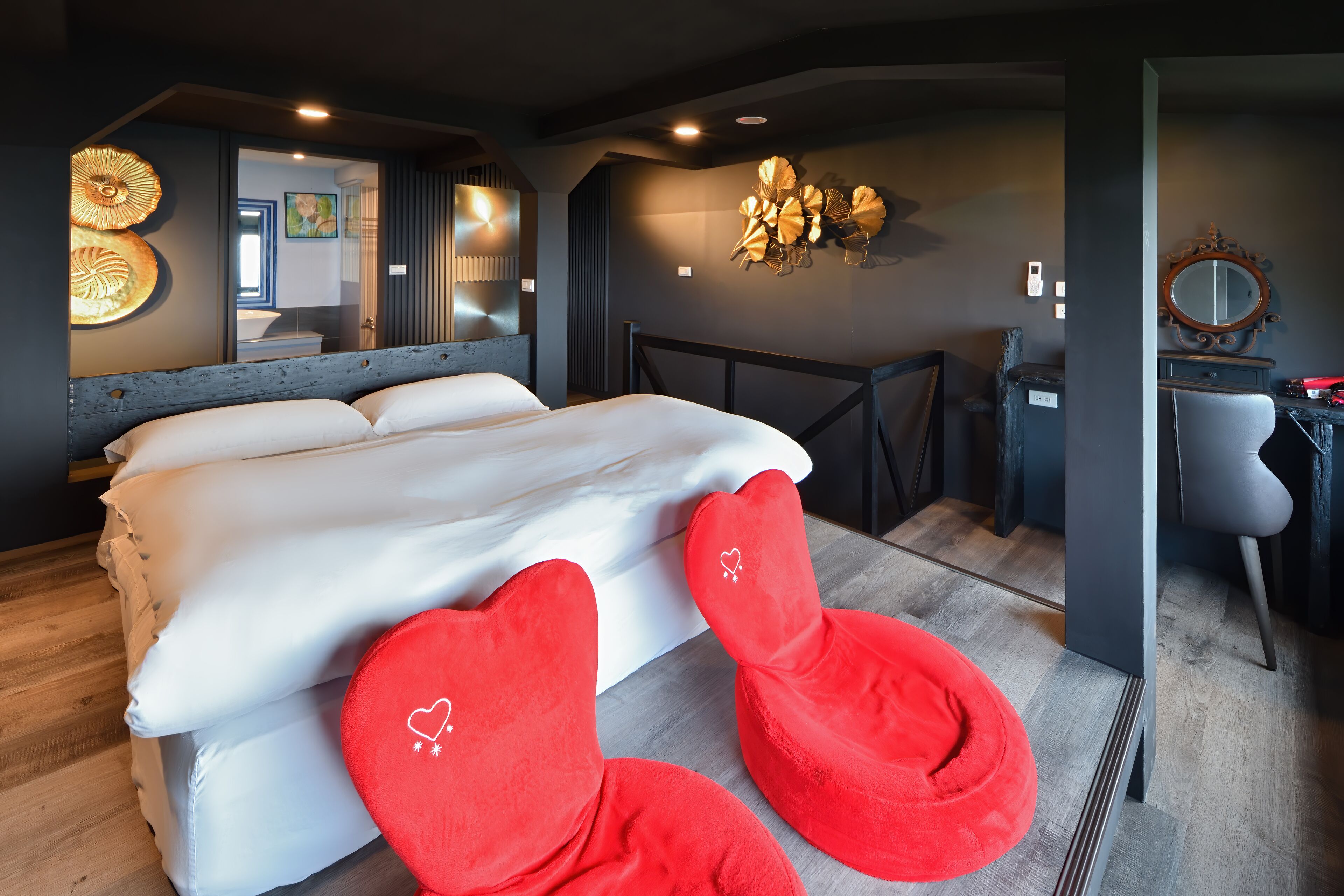 Quarto com uma cama grande, um espelho e uma cadeira vermelha.