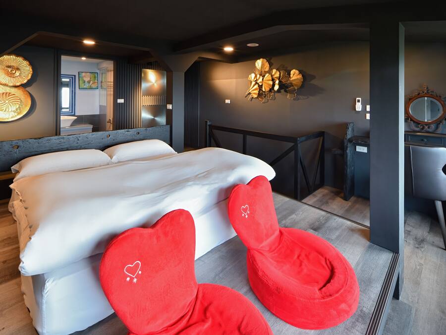 Quarto com uma cama grande, um espelho e uma cadeira vermelha.