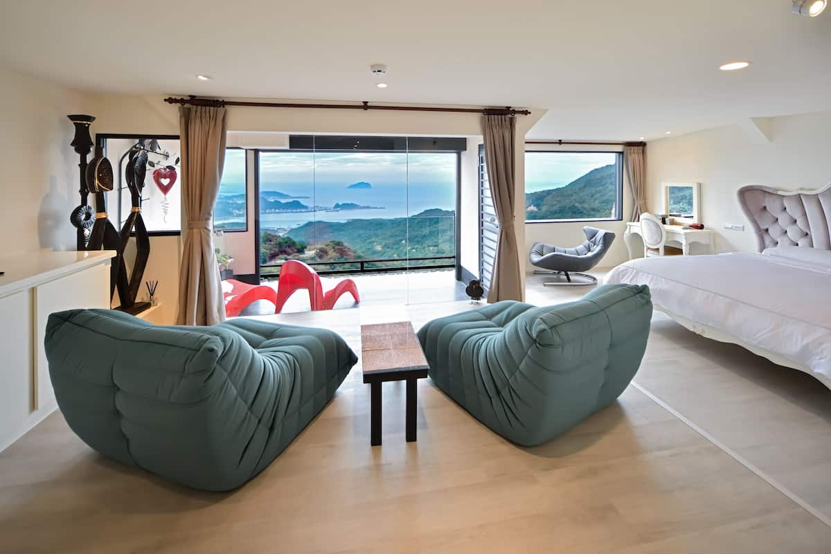 A modern hotel room with a large bed, a desk, and a view of the mountains.