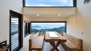 A modern room with a large window offering a view of hills and a body of water. There are two wooden benches and a table in the center. - Windsor's Sunlight Han-Guan (New Taipei City)
