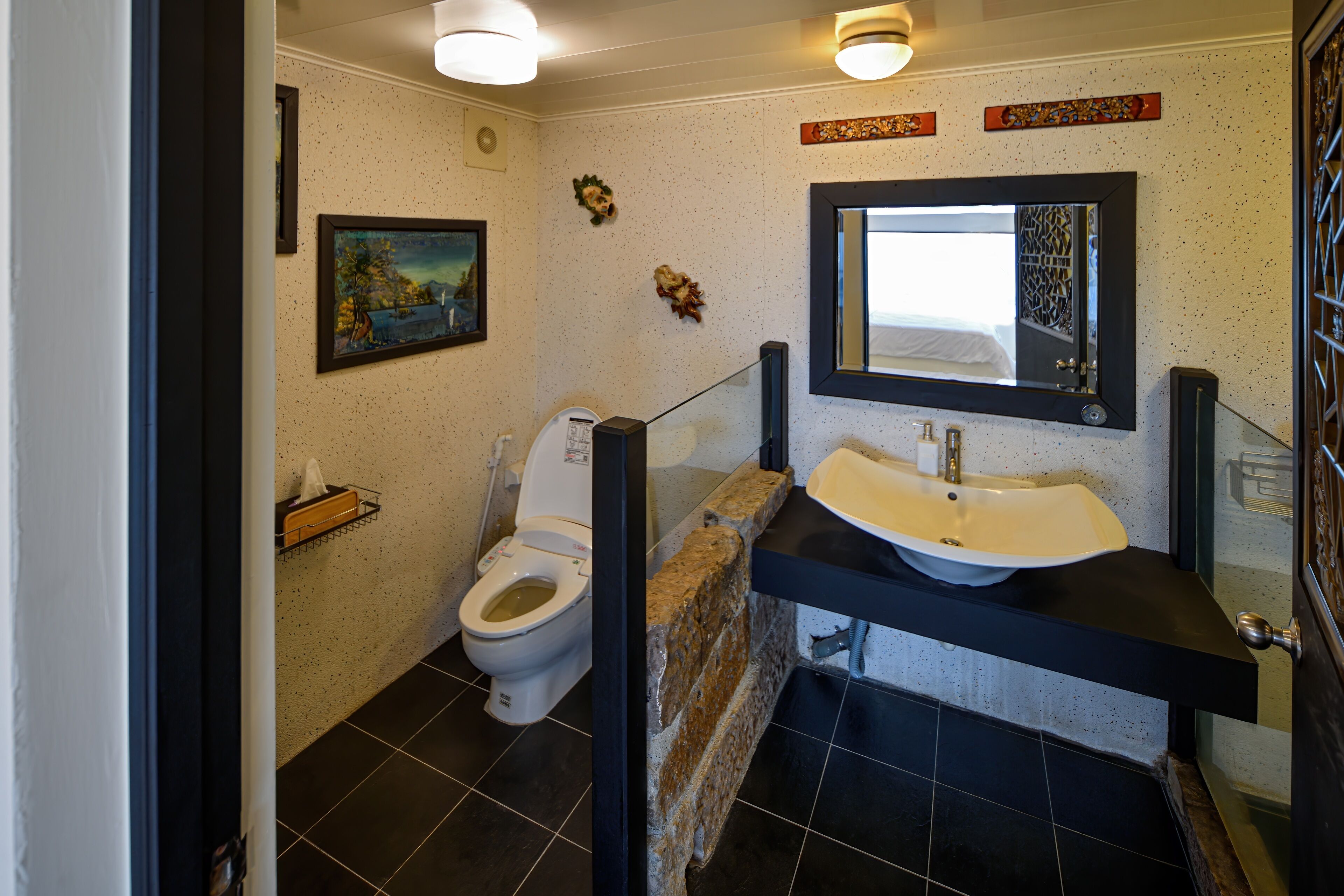 A bathroom with a toilet, sink, and mirror.