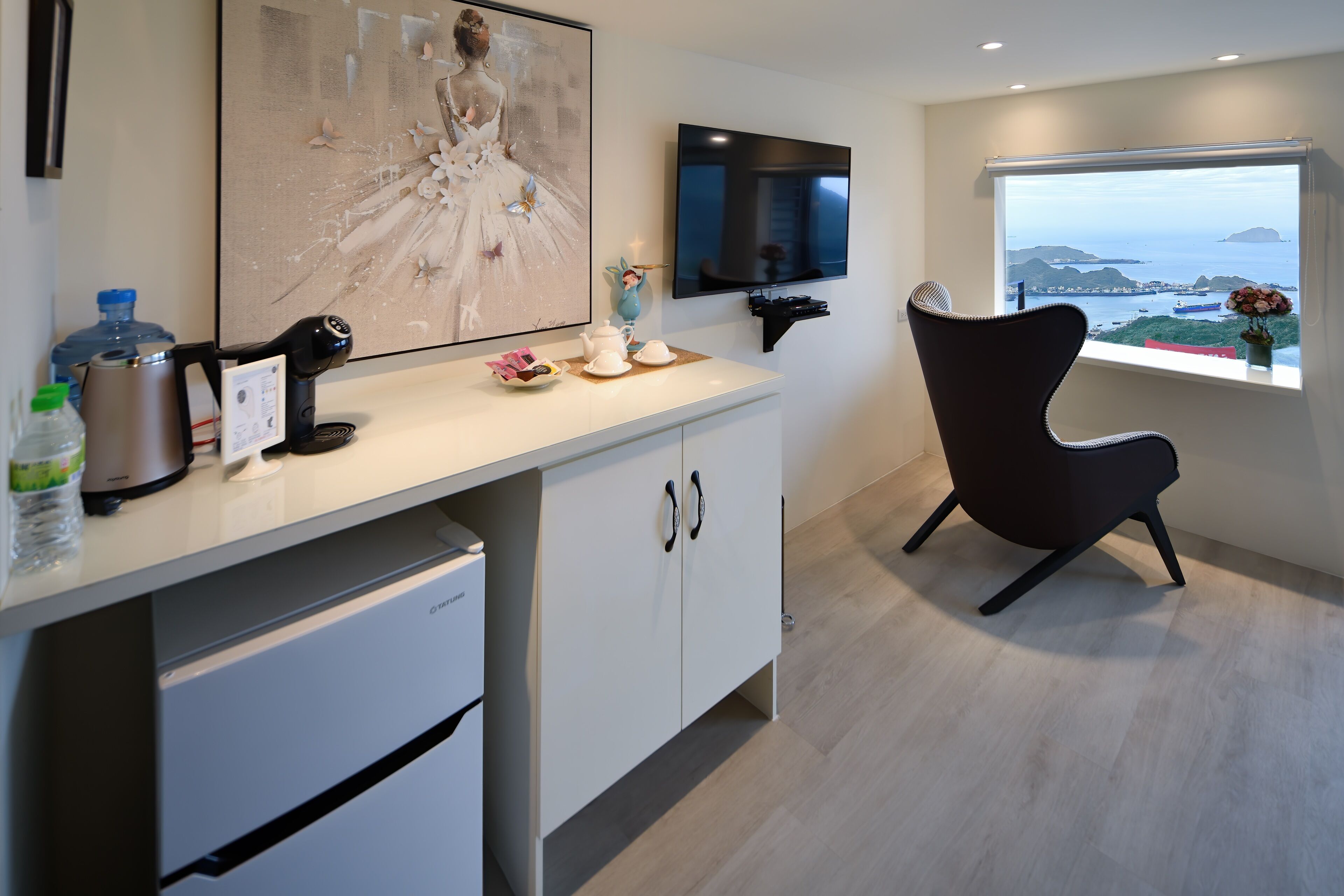 A modern kitchen with a large window, a flat-screen TV, and a decorative painting.