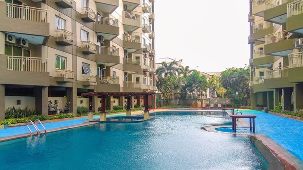A swimming pool surrounded by multi-story residential buildings with balconies. - Comfy Studio at Menara Kondominium Kelapa Gading Apartment (Jakarta)