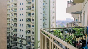 A high-rise residential building with multiple balconies, some with plants. - Comfy Studio at Menara Kondominium Kelapa Gading Apartment (Jakarta)