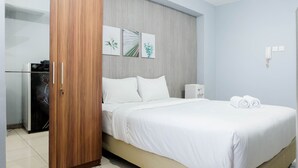 Una habitación de hotel con cama, armario y escritorio con lámpara.
