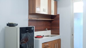 Una cocina compacta con armarios de madera, una encimera blanca y un refrigerador empotrado.