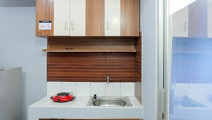 Cocina compacta con armarios de madera, pileta de acero inoxidable y cocina por inducción roja.