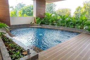A swimming pool with a wooden deck and surrounding greenery.