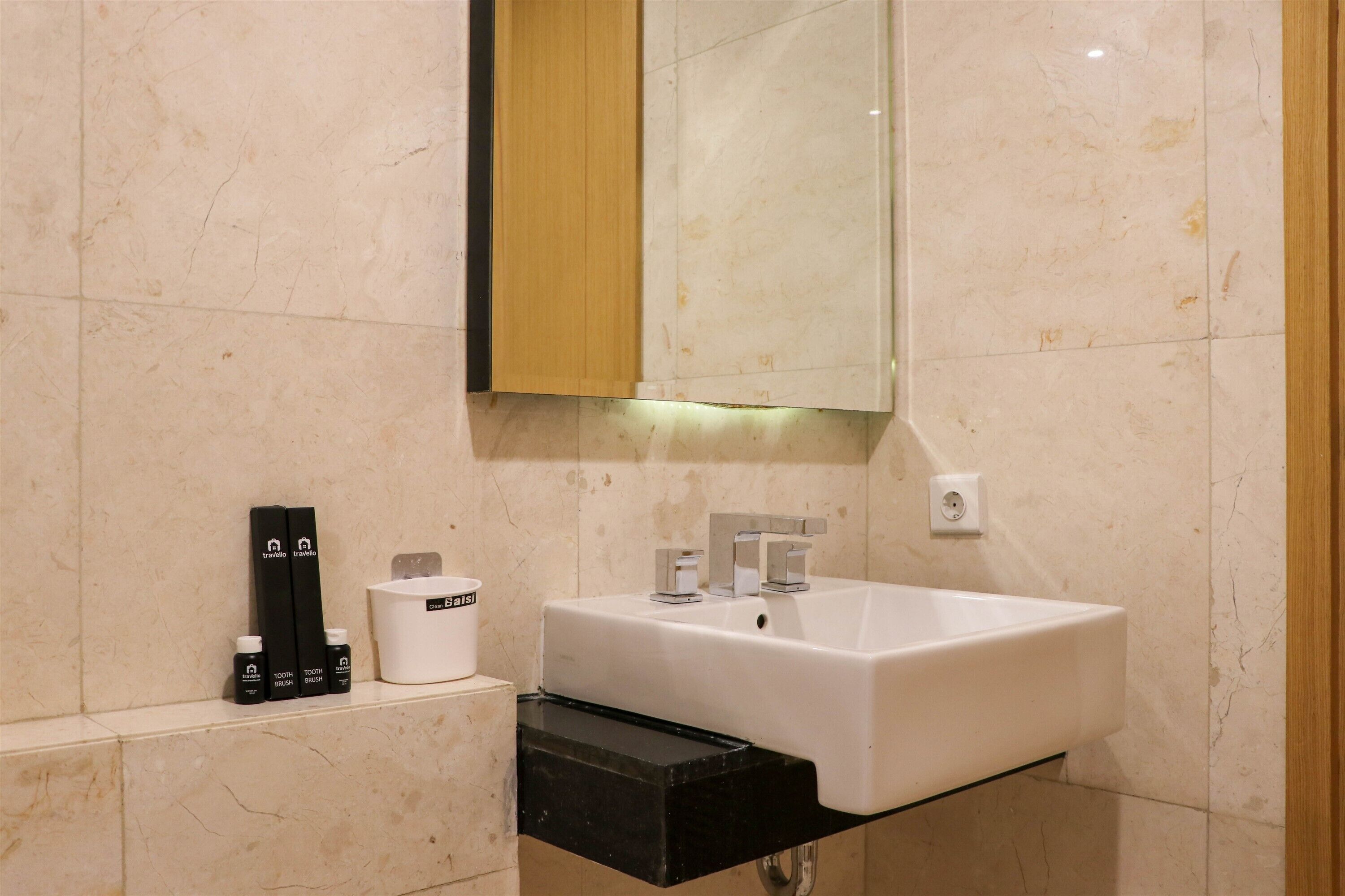 A modern bathroom with a white sink, a mirror, and toiletries on the counter.