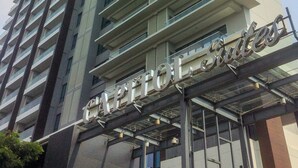 A high-rise hotel with a modern design, featuring a prominent 'Capitol Suites' sign at the entrance. - Spacious Studio Room at Capitol Suites Apartment (Jakarta)