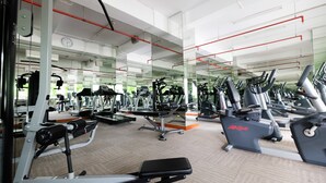 Un gimnasio con varias máquinas de ejercicio, espejos y suelo alfombrado.
