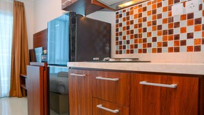 Cocina pequeña con armarios de madera, un refrigerador negro y un revoque de azulejos.