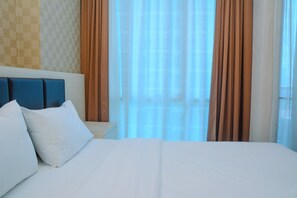 Een hotelkamer met een groot bed, een nachtkastje en een hoofdbord met blauwe kussens.