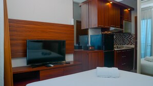 Habitación de hotel con cama, televisión, minibar, pequeña cocina y baño.
