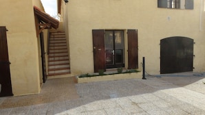 A narrow stone-paved courtyard with a wooden staircase leading to a door with wooden shutters. - Les Pucines (Six-Fours-les-Plages)