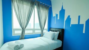 A neatly made bed with white linens and rolled towels, a cityscape mural on the wall, and a window with curtains. - Minimalist 2BR Apartment at Springhill Terrace Residence (Jakarta)