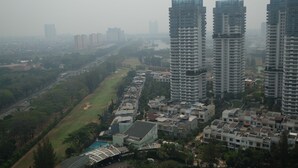 A high-rise residential building complex with multiple floors, surrounded by smaller houses and a park area. - Minimalist 2BR Apartment at Springhill Terrace Residence (Jakarta)