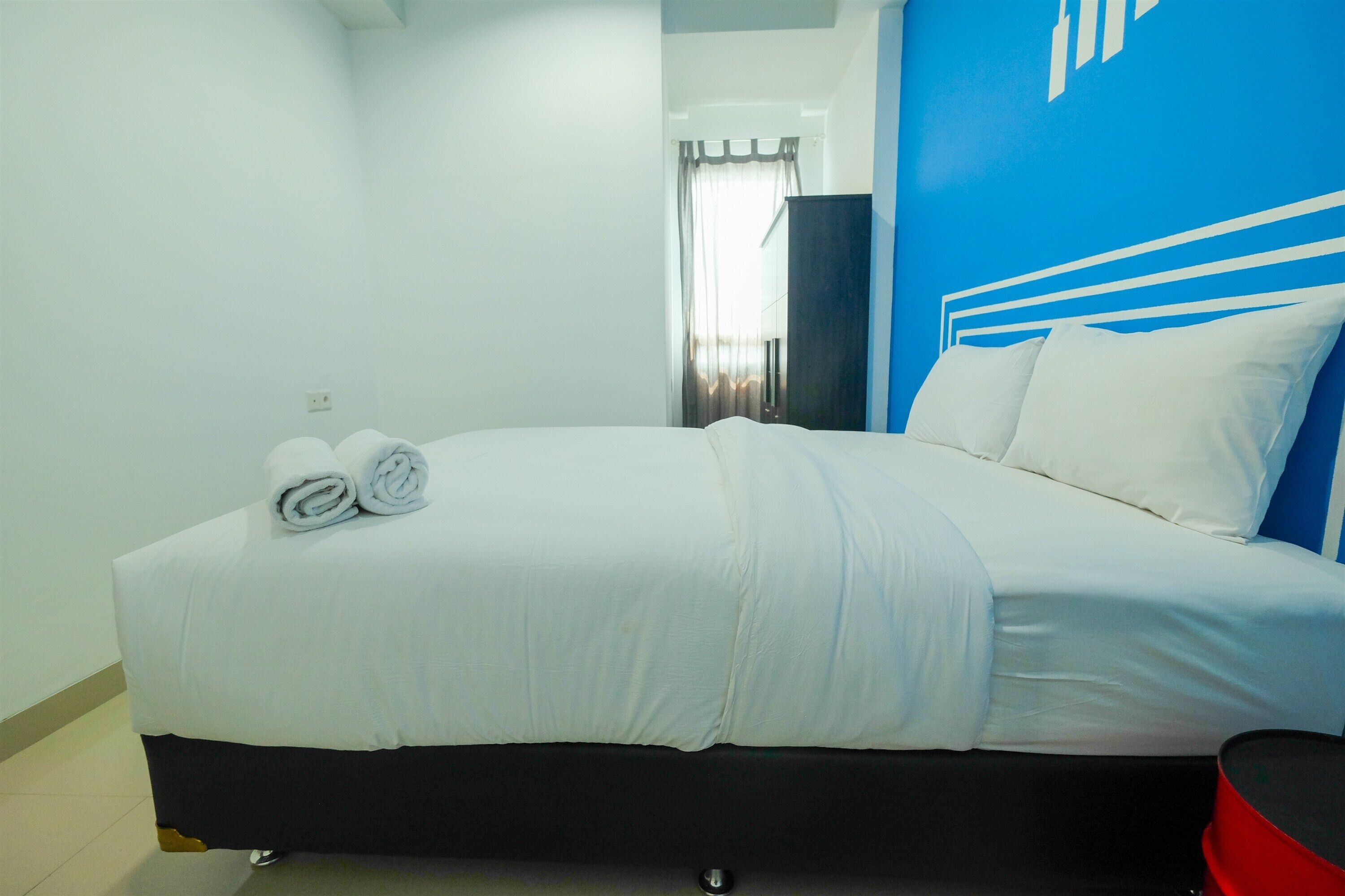 Une chambre d’hôtel avec un lit, un fauteuil rouge et un mur d’accent bleu.